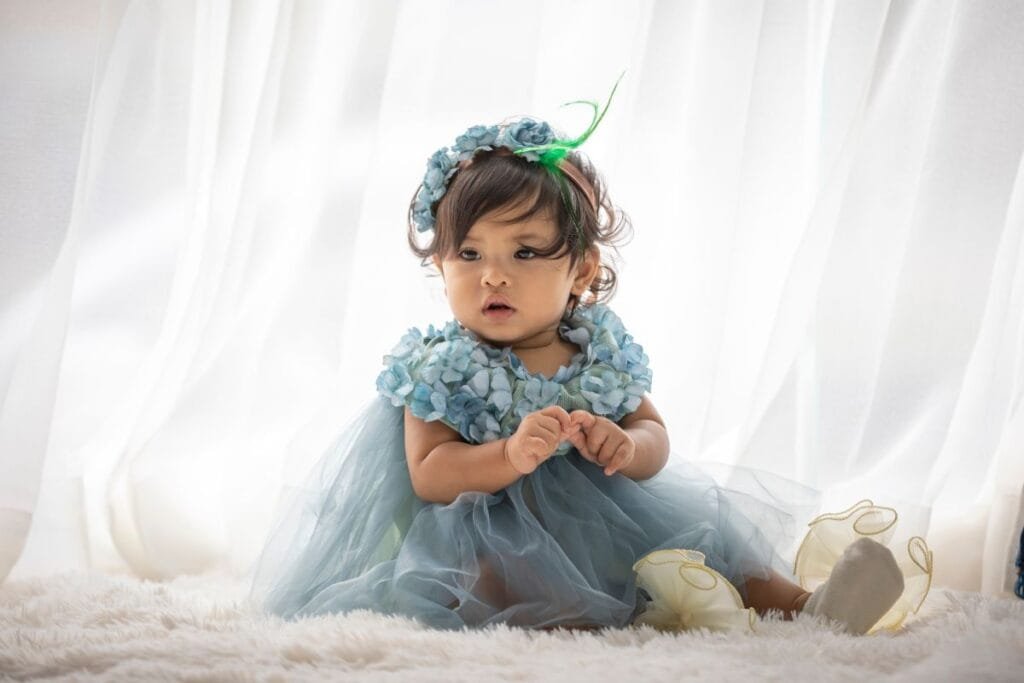 A cute little munchkin wearing a pretty dress with floral detailing