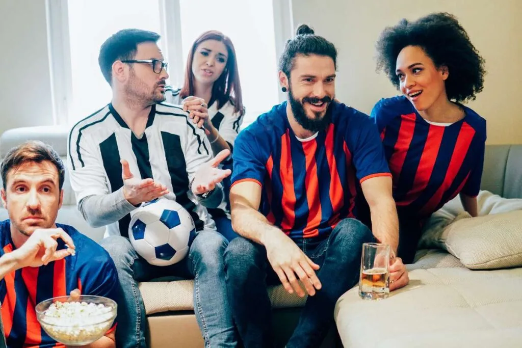 A group of friends wearing jerseys while watching a match.
